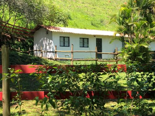 une petite maison blanche avec une clôture rouge devant elle dans l'établissement Vivenda dos Guaranys: casa + loft, à Conservatória