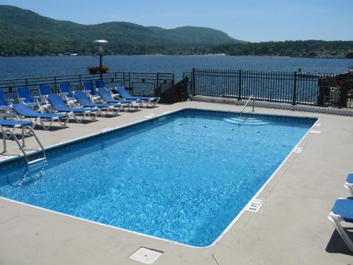 a swimming pool with chairs and a body of water at The Lake Motel in Lake George
