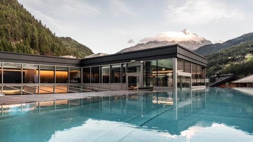 a house with a swimming pool in front of a mountain at die berge lifestyle-hotel Sölden in Sölden