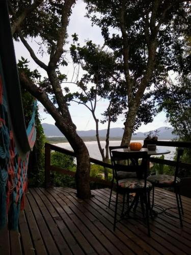 a table and chair on a deck with a view of the water at Hostel do Morro in Florianópolis