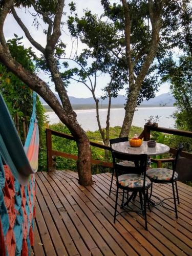a table and chairs on a deck with a view of the water at Hostel do Morro in Florianópolis