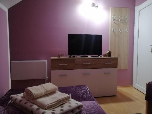 a living room with a tv and a ottoman with towels at Apartman NECA Zlatar in Nova Varoš