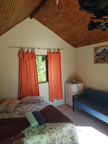 una camera da letto con tende arancioni, un letto e un divano di Recanto JF da Serra a São Thomé das Letras