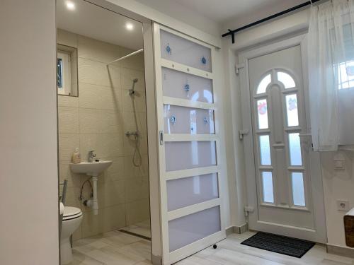 a bathroom with a shower and a toilet and a glass door at Érdi Muskátlis Vendégház in Érd