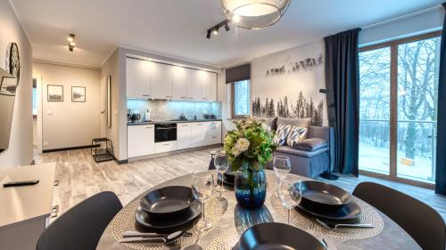 cocina y sala de estar con mesa de comedor con sillas en Apartamenty ROYAL APARTS VIP Widok 800 - z panoramą gór, en Szklarska Poręba