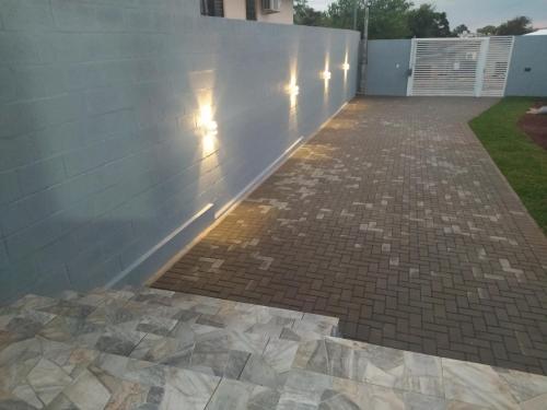 a brick patio with a white wall and a sidewalk at Trentino 66 - Hospedagem em Ijuí, casa agradável com estacionamento in Ijuí