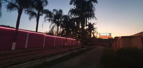 uma rua com uma cerca e palmeiras e uma placa em Desejo Motel em Araçoiaba da Serra