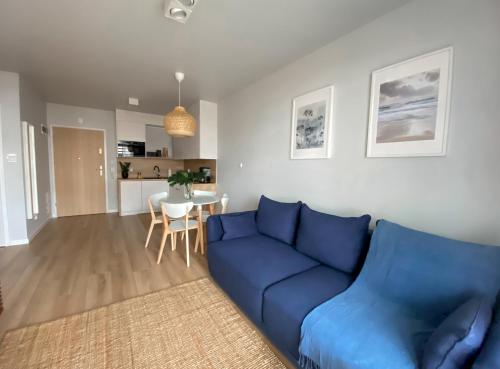 a living room with a blue couch and a table at Urokliwy apartament HAVEN nad morzem+free parking in Kołobrzeg