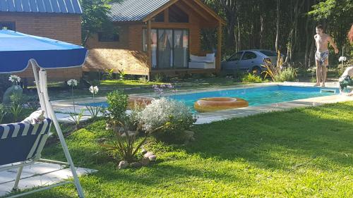 una piscina en un patio con una casa en Cabañas El Druida en Villa General Belgrano