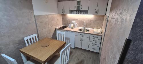 uma pequena cozinha com uma mesa e um lavatório em Apartmani Božović em Nova Varos