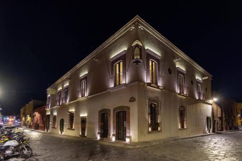 a white building with motorcycles parked outside of it at night at Casa 1810 Parque Hotel Boutique in San Miguel de Allende