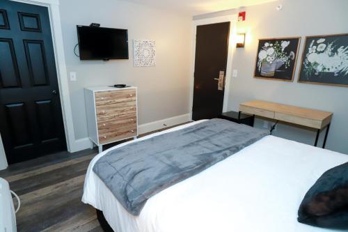 a bedroom with a bed and a dresser and a television at Gunstock Inn & Suites in Gilford