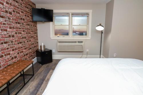 a bedroom with a bed and a brick wall at Gunstock Inn & Suites in Gilford