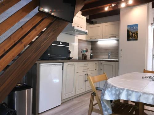 une cuisine avec des armoires blanches et une table à l'intérieur dans l'établissement APPARTEMENT CAUTERETS POUR 4 PERSONNES AVEC PARKING, à Cauterets