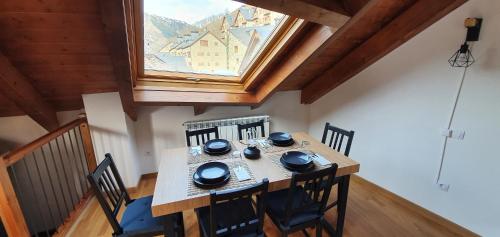 a dining room table with chairs and a large window at Dúplex amb altell de luxe + parking (Taüll) in Taull