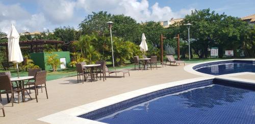 a patio with tables and chairs and a swimming pool at Apartamento na Reserva Imbassai in Imbassai