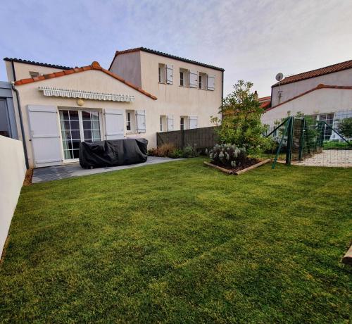 une arrière-cour d'une maison avec une pelouse dans l'établissement Maison le Havre de la Gachère, 2 chambres, 2 salles d'eau, parking privé et jardin, à Brem-sur-Mer