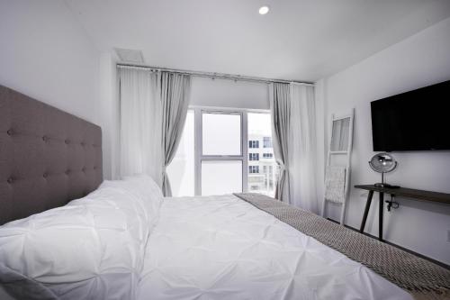a white bedroom with a large bed and a window at Stylish luxury condo, central location, ocean view, pool, gym in Oranjestad