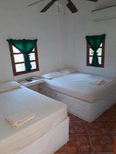 two beds in a room with two windows at Cabañas Guicci Resort in San Carlos