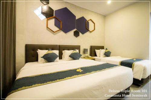 a bedroom with two beds with white sheets and blue pillows at Casananta Seminyak in Seminyak