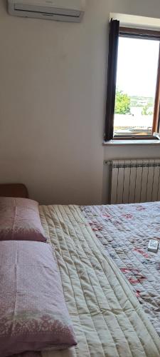 1 dormitorio con 1 cama con ventana y edredón en Casa Vacanze Cerreto 1 en Miglianico