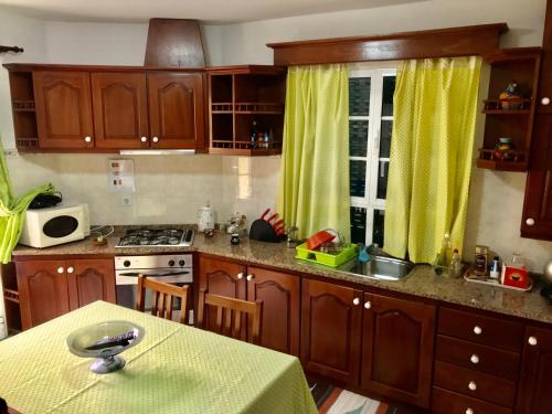 a kitchen with wooden cabinets and a table with a yellow table cloth at Terra Chã Cottage,FEEL Home, in São Vicente