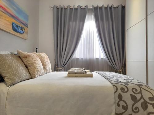 a bedroom with a large white bed with a window at Cozy Rooms - Great Bus Connections - Free Parking in Mosta
