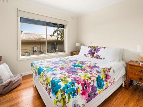 a bedroom with a bed with a colorful comforter and a window at Rhyll Relaxer in Rhyll