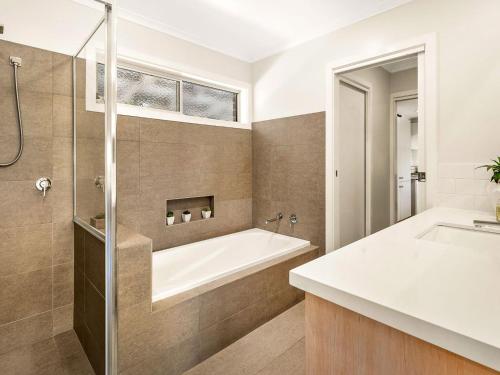 a bathroom with a bath tub and a sink at Rhyll Relaxer in Rhyll