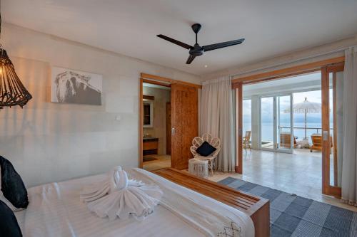 a bedroom with a bed with a ceiling fan at Aqua Nusa - Luxury Lembongan Villas in Nusa Lembongan