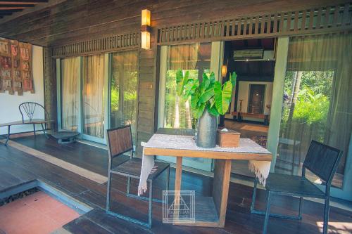 a table and chairs on a porch with a plant at Baan Suan Residence เฮือนพักบ้านสวน in Chiang Mai