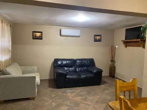 a living room with a black leather couch at Cabaña el Pino 1 in Creel