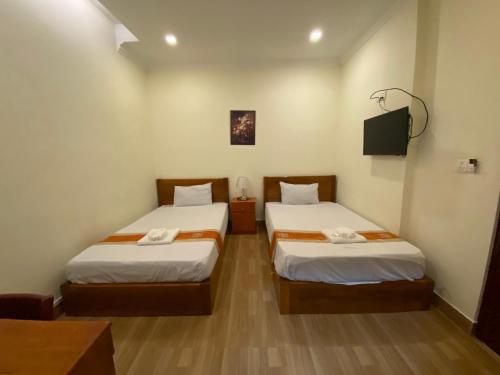 a room with two beds and a tv in it at Phnom Penh Le Vincent Hotel in Phnom Penh