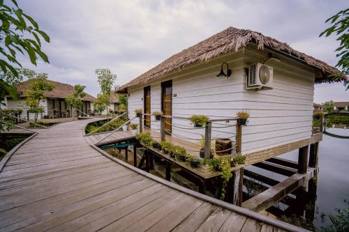 a wooden walkway leading to a house on the water at Good Time Relax Resort in Kampot