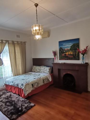 a bedroom with a bed and a fireplace and a chandelier at QTEN CASINO in Pietermaritzburg