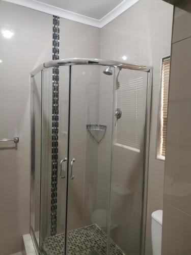 a shower with a glass door in a bathroom at QTEN CASINO in Pietermaritzburg