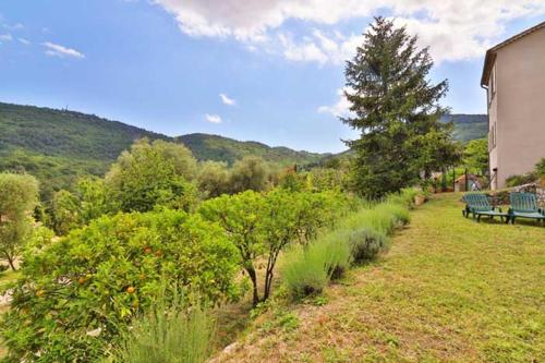 une cour avec bancs et arbres et un bâtiment dans l'établissement Appartement moderne au Bar-sur-Loup - Terrasse & vue, à Le Bar-sur-Loup