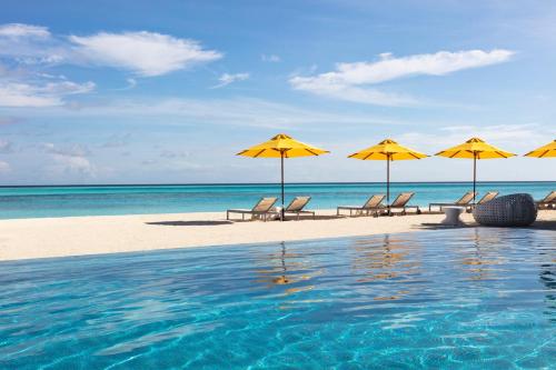 a swimming pool with chairs and umbrellas on the beach at Niyama Private Islands Maldives in Dhaalu Atoll