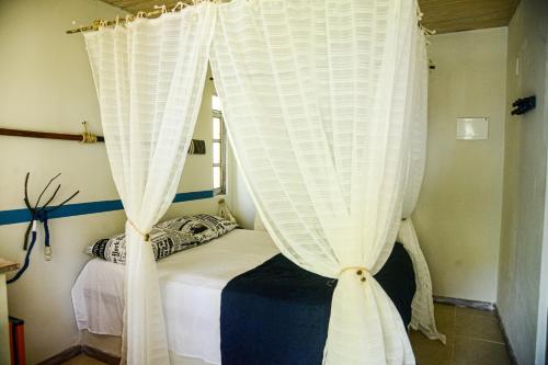 a bed with white curtains in a room at Pousada Bellatrix Ecolodge in Praia do Forte