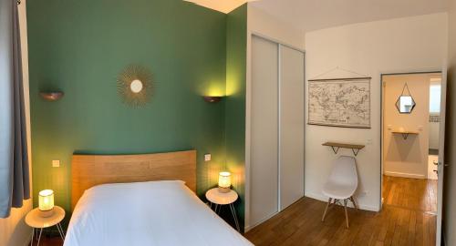 ein Schlafzimmer mit einem weißen Bett und einer grünen Wand in der Unterkunft Le Jeanne d'Arc - Appartements meublés in Gien