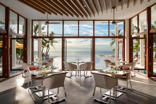 a dining room with tables and chairs and large windows at Niyama Private Islands Maldives in Dhaalu Atoll