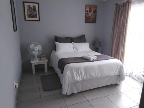 比勒陀利亚Cottage @19th的卧室里有一张白色的大床，床边有一扇窗户