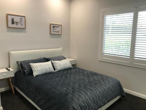 a bedroom with a bed and a window at Sunnyside Retreat - Holiday Home - Walk to Nobbys or Flynns Beach , enjoy the sound of waves and birds in Port Macquarie