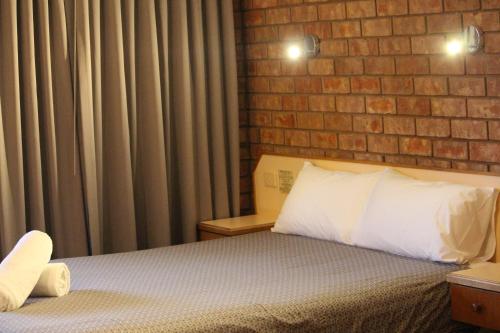 a bedroom with a bed and a brick wall at Red Cliffs Colonial Motor Lodge, Mildura Region in Red Cliffs