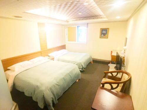 a hotel room with two beds and a chair at Best Hotel in Taipei