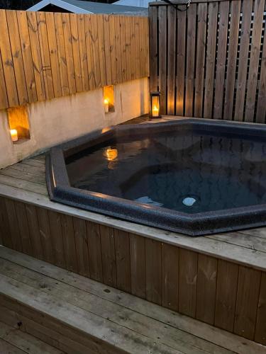 a hot tub on a wooden deck with lights at Varmi Guesthouse Apartments & rooms in Hveragerði