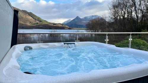 a jacuzzi tub with a view of the mountains at The Heronry Hideaway with luxury hot tub in Ballachulish