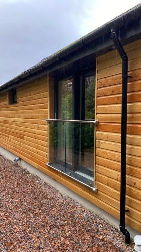 a cabin with a balcony on the side of it at The Heronry Hideaway with luxury hot tub in Ballachulish