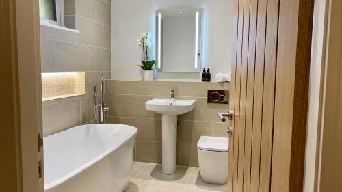a bathroom with a sink and a tub and a toilet at The Heronry Hideaway with luxury hot tub in Ballachulish