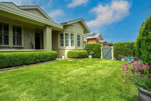 a house with a yard with green grass and flowers at 'Micah House' A Central Mudgee Art Deco Hideaway in Mudgee
